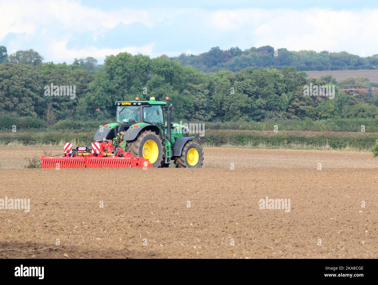 Tracor breaking up the earth ready to sow seeds. Common agricultural scene in United Kingdom. Stock Photo