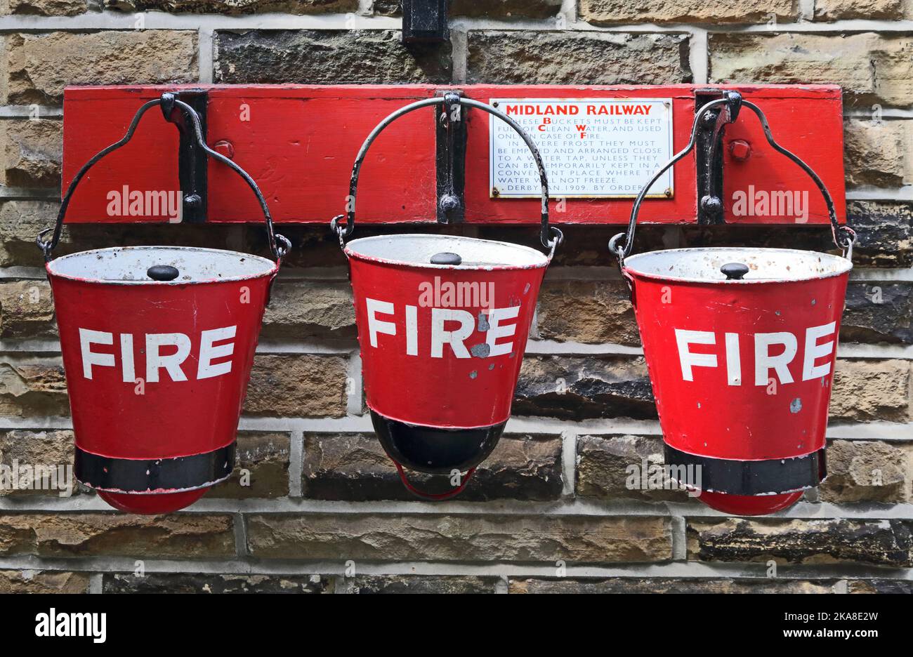 Old, red Fire buckets on hangers, Ingrow West railway station, Keighley and Worth Valley Railway Stock Photo