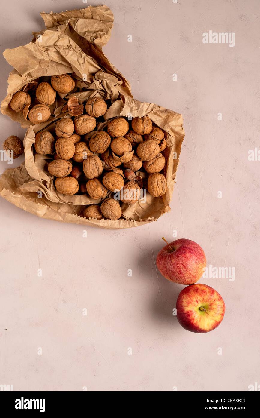 Two apples, and some walnuts, on a delicate pink background. Stock Photo