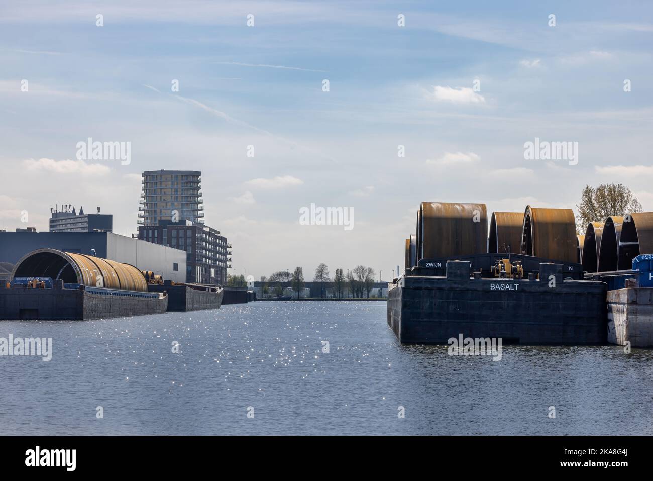 A closeup of barges with monopiles in an industrial harbor in Roermond Stock Photo