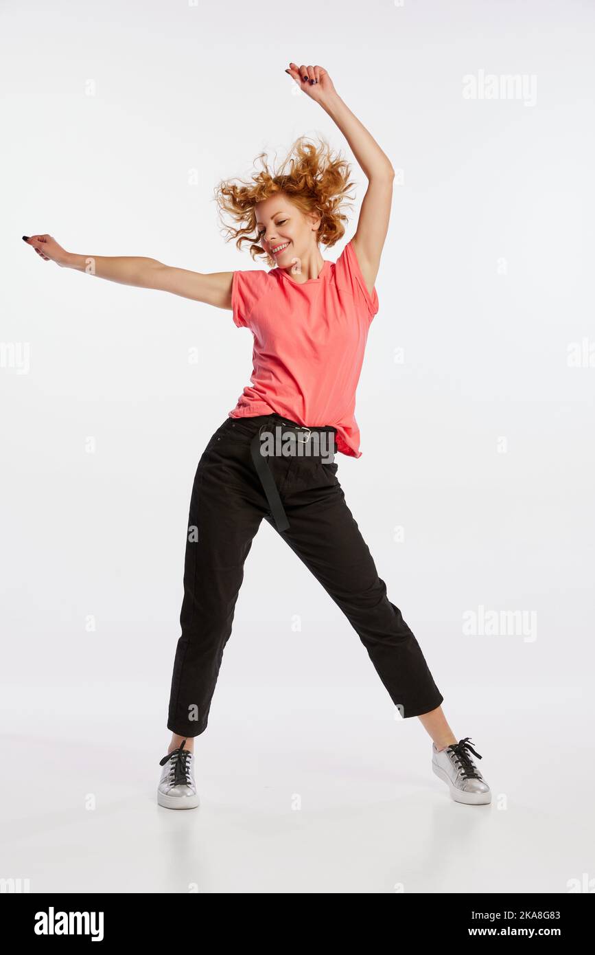 Excited beautiful young redheaded woman dancing isolated on white