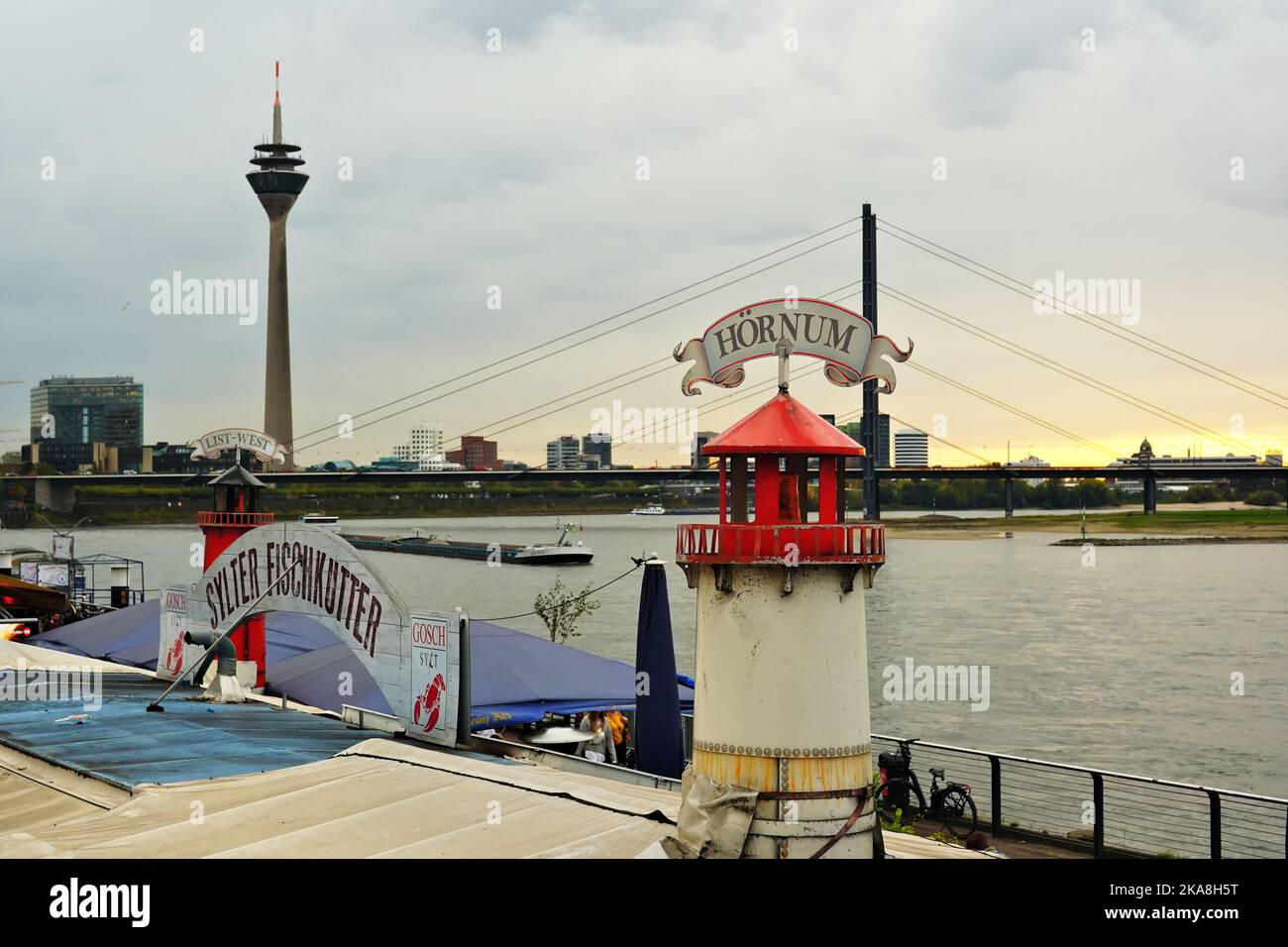 Scenery at Rhine river in Düsseldorf/Germany with decorational lighthouse at an outdoor restaurant. Rhine Tower in the background. Stock Photo