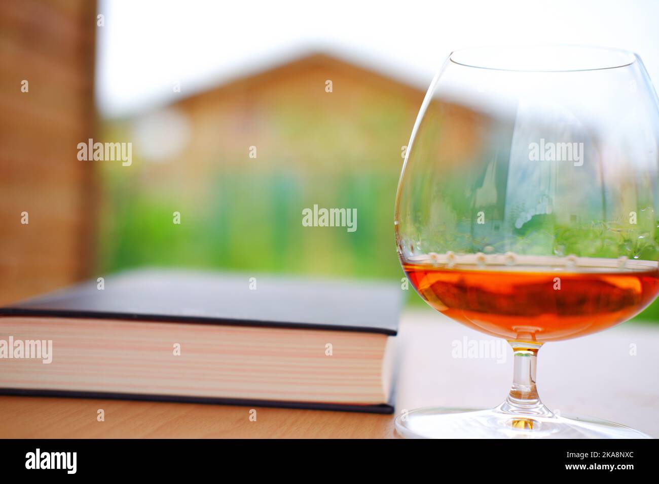 Whiskey in snifter glass and book outdoor on table Stock Photo