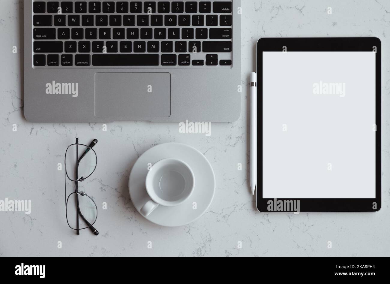 Opened laptop with digital tablet with white blank screen. On marble table, workplace Stock Photo