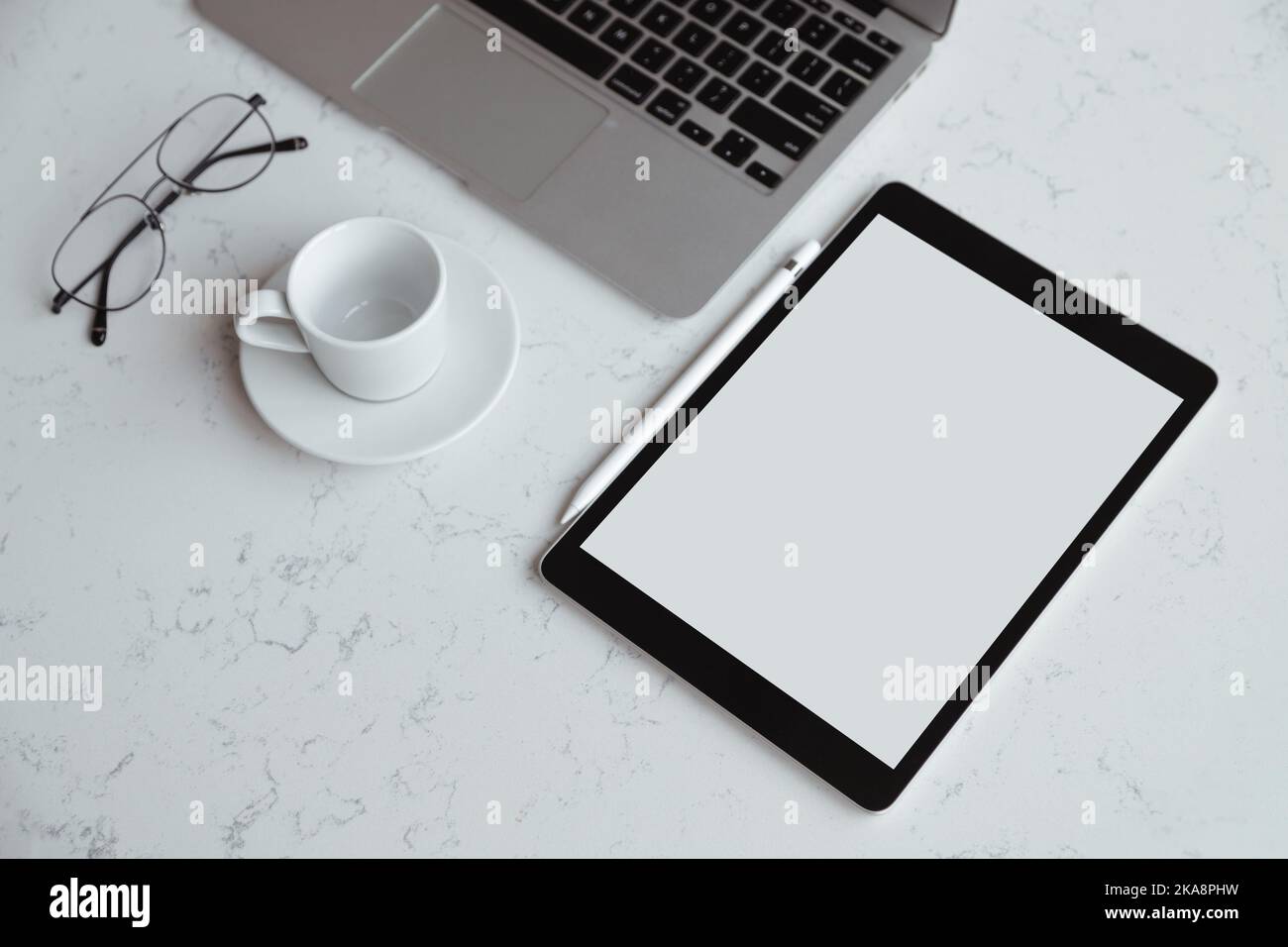 Opened laptop with digital tablet with white blank screen. On marble table, workplace Stock Photo