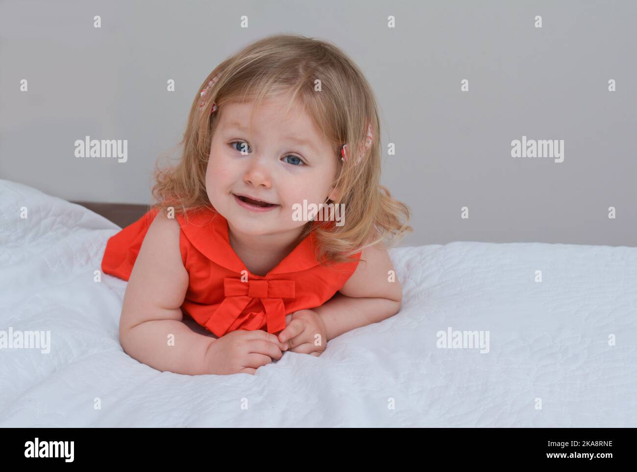 Portrait of a two year old girl with blue eyes in a red dress Stock