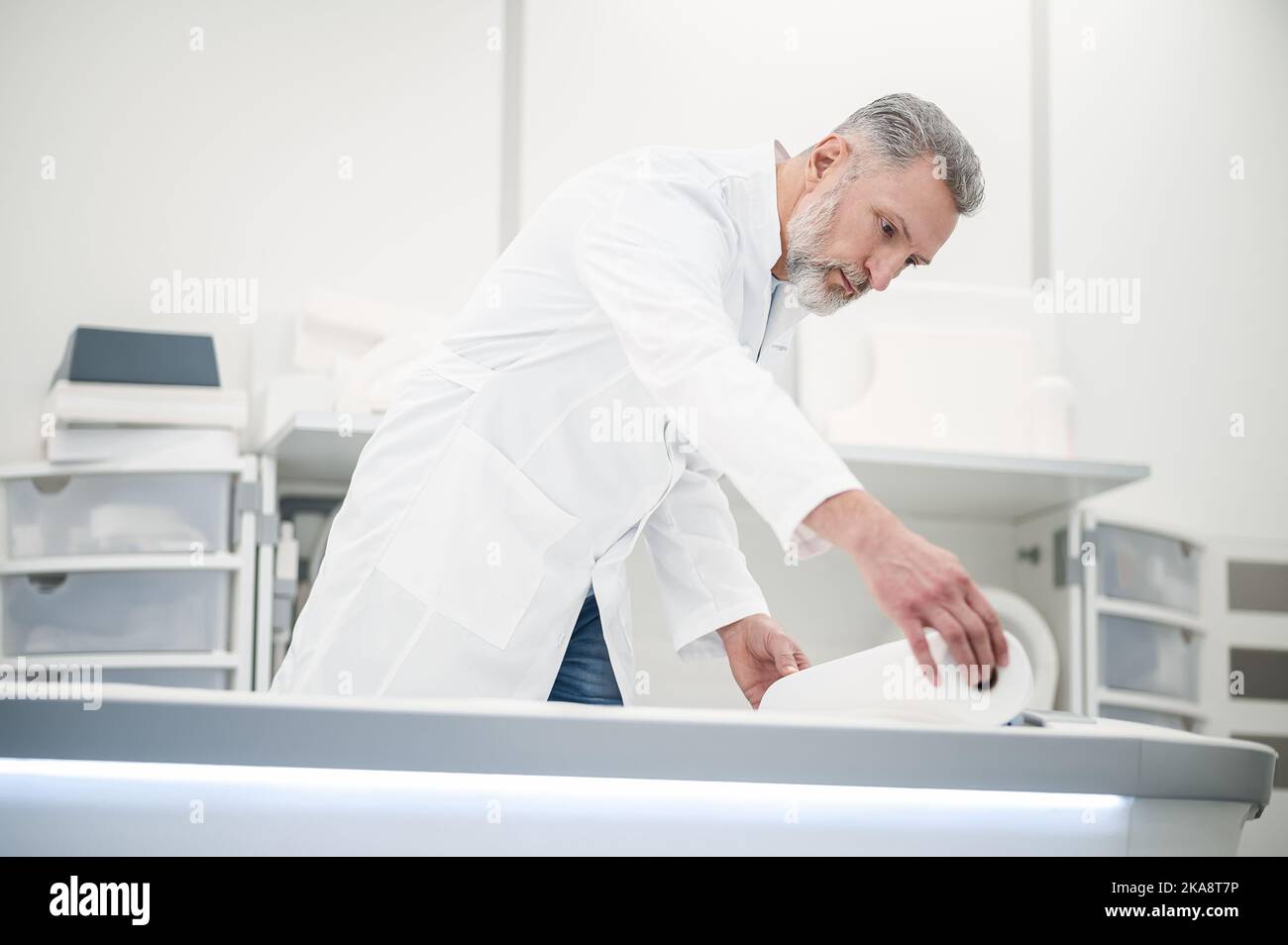 Male gray-haired doctor in a lab coat working in diagnostic center Stock Photo