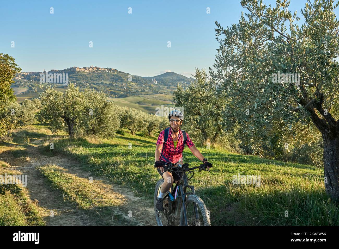 nice senior woman riding her electric mountain bike between olive trees