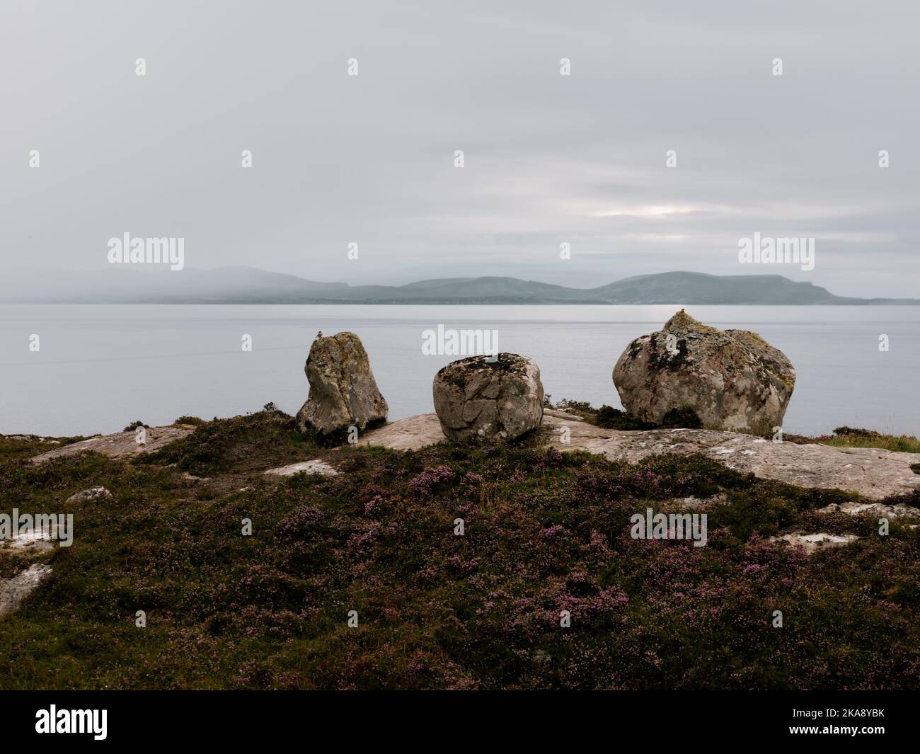 A distant view of the Isle of Skye and the dusk rock and heather landscape of South Erradale near Gairloch on the west coast of Scotland UK Stock Photo