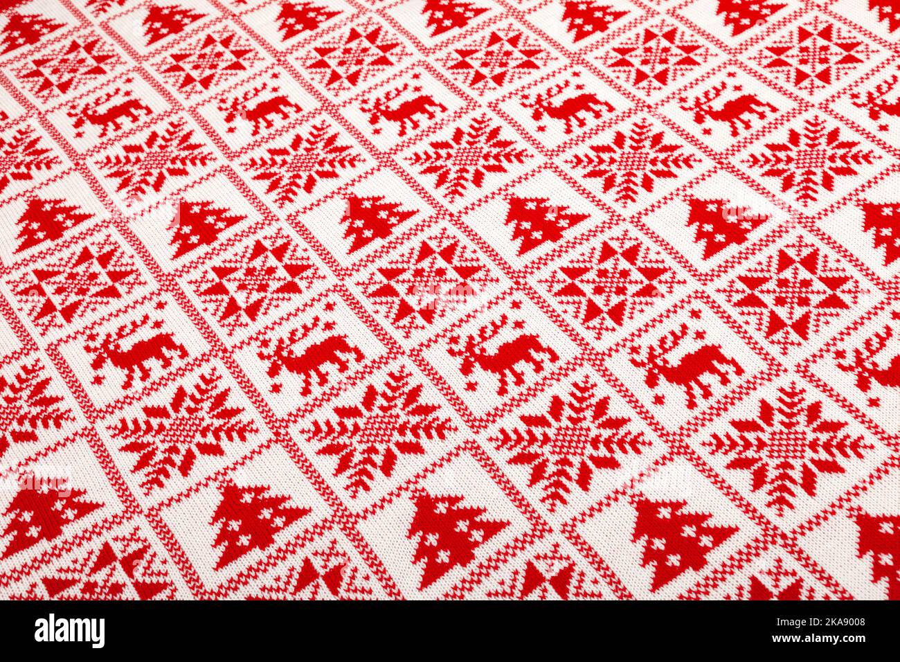 White knitted fabric with red  moose, fir tree and snowflake Scandinavian style geometric ornament cristmas background Stock Photo