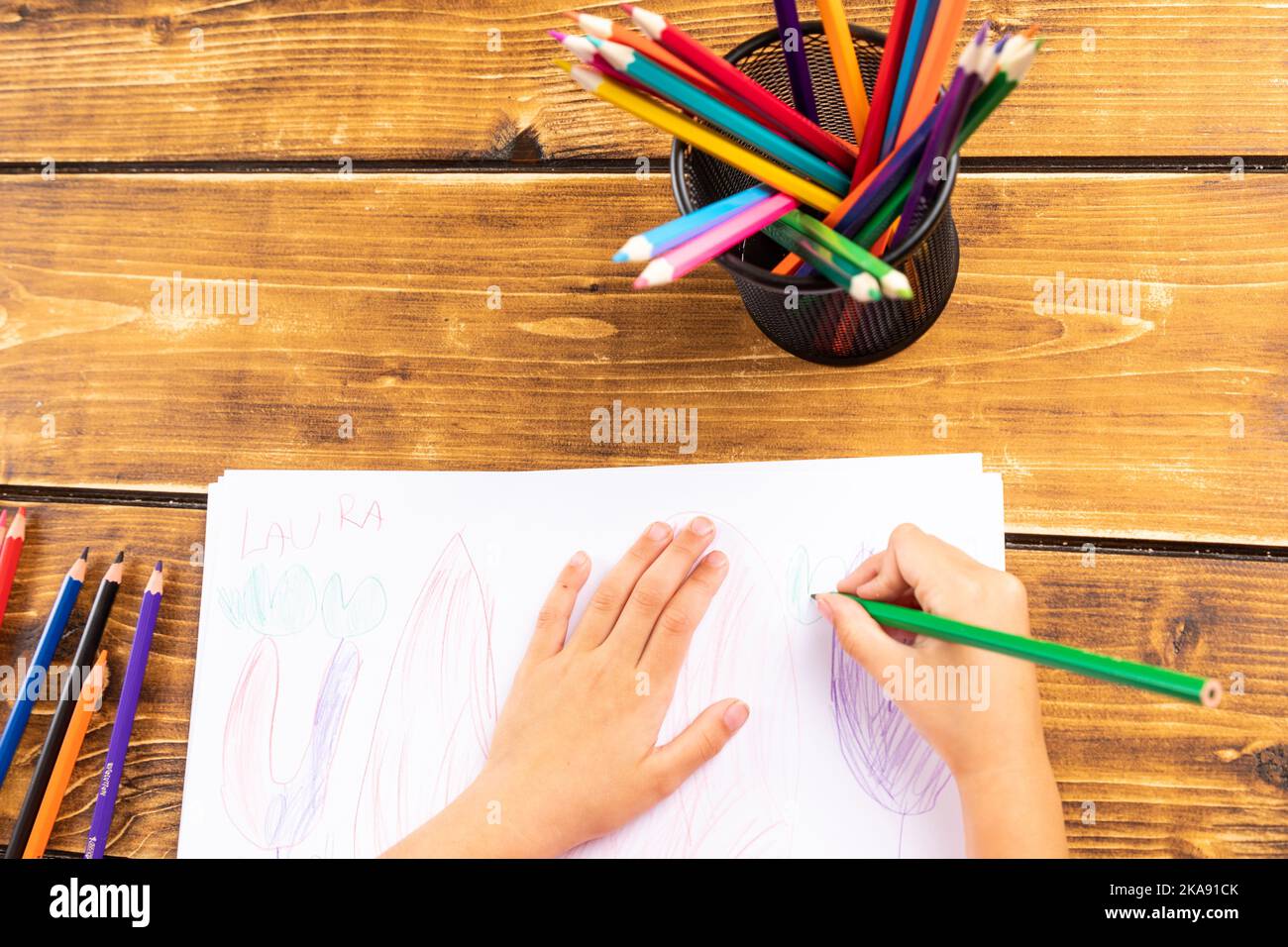 The child drawing with colorful pends on wooden desk Stock Photo