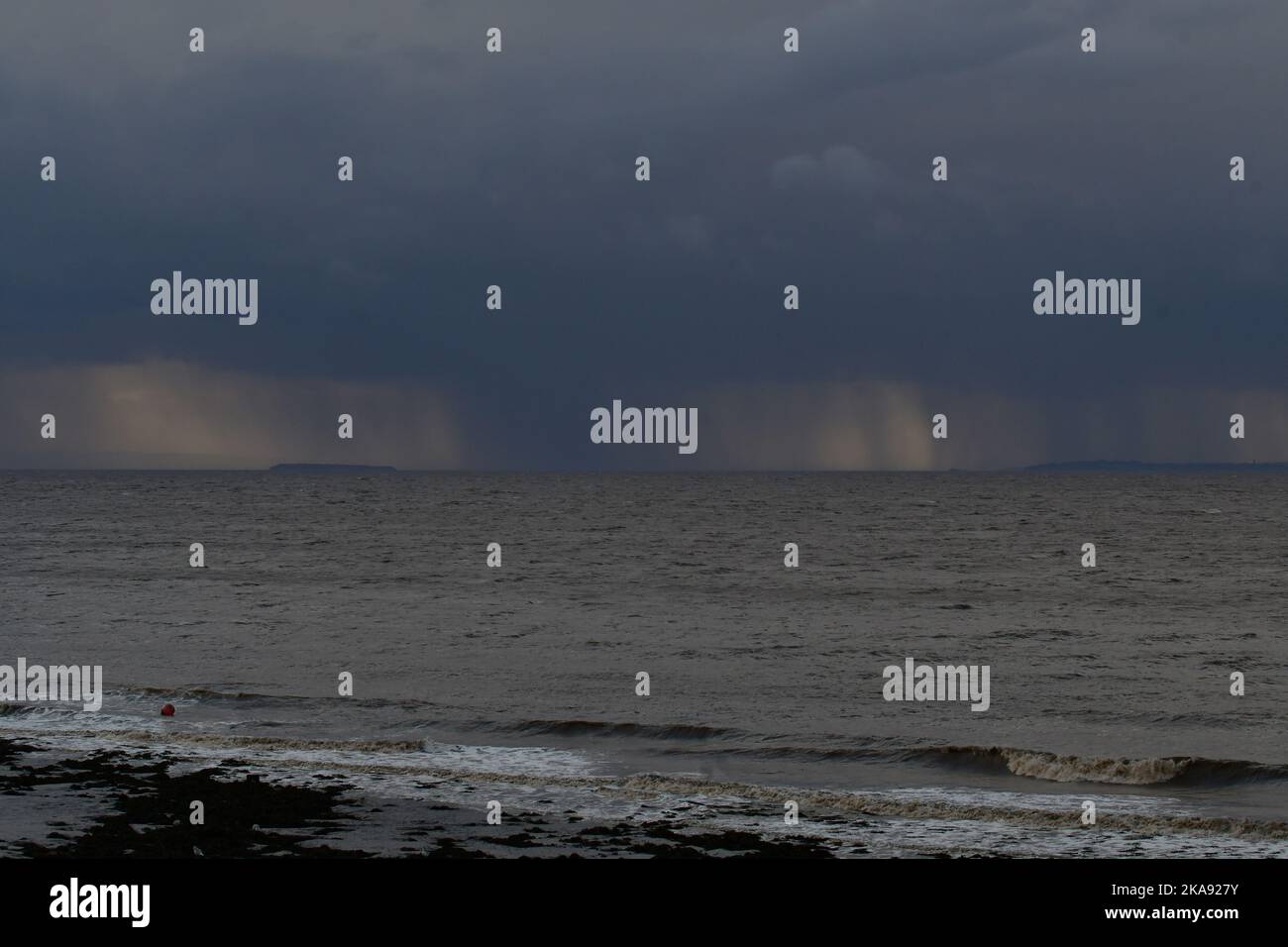Clevedon, UK. 01st Nov, 2022. UK Weather. On a cold and windy afternoon at Clevedon Seafront, Wales on the far side of Clevedon beach Storm Claudio is seen with Menacing Storm Clouds dumping rain along their coast line. Picture Credit: Robert Timoney/Alamy Live News Stock Photo