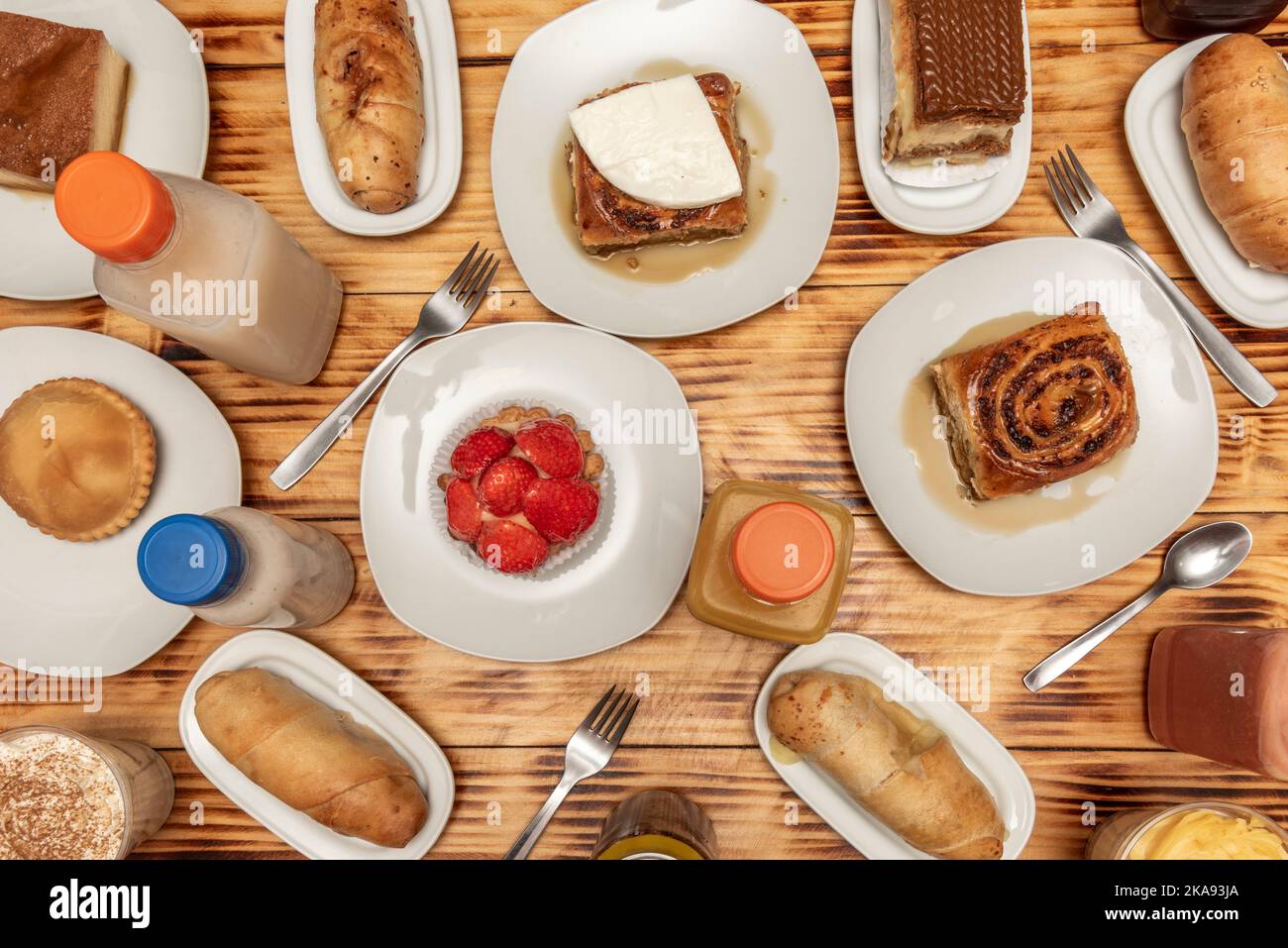 Typical Venezuelan and Latin desserts, golfeados, creams, quesillos, stuffed pieces and strawberry tartlet on a charred pine wood table Stock Photo