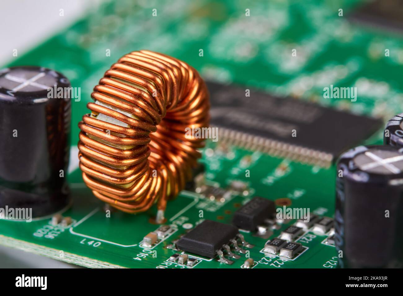 Orange inductor with copper wire on green printed circuit board detail