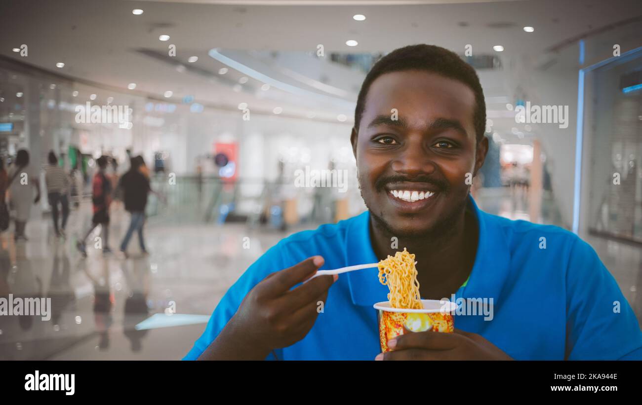 African man eats instant noodle soup in rush hour. Concept of urban