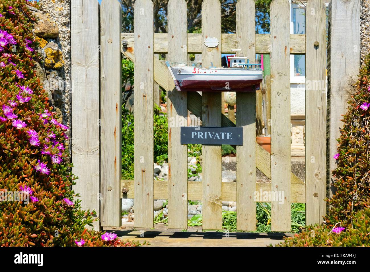 A quirky wooden gate with a model ship on the South West Coast Path at ...
