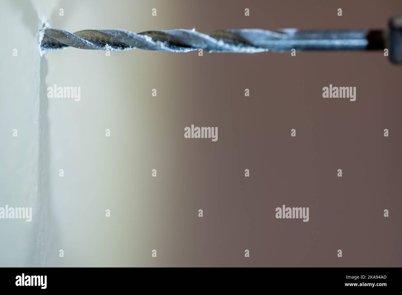 Selective focus on point of of a drill bit making a pilot hole in drywall Stock