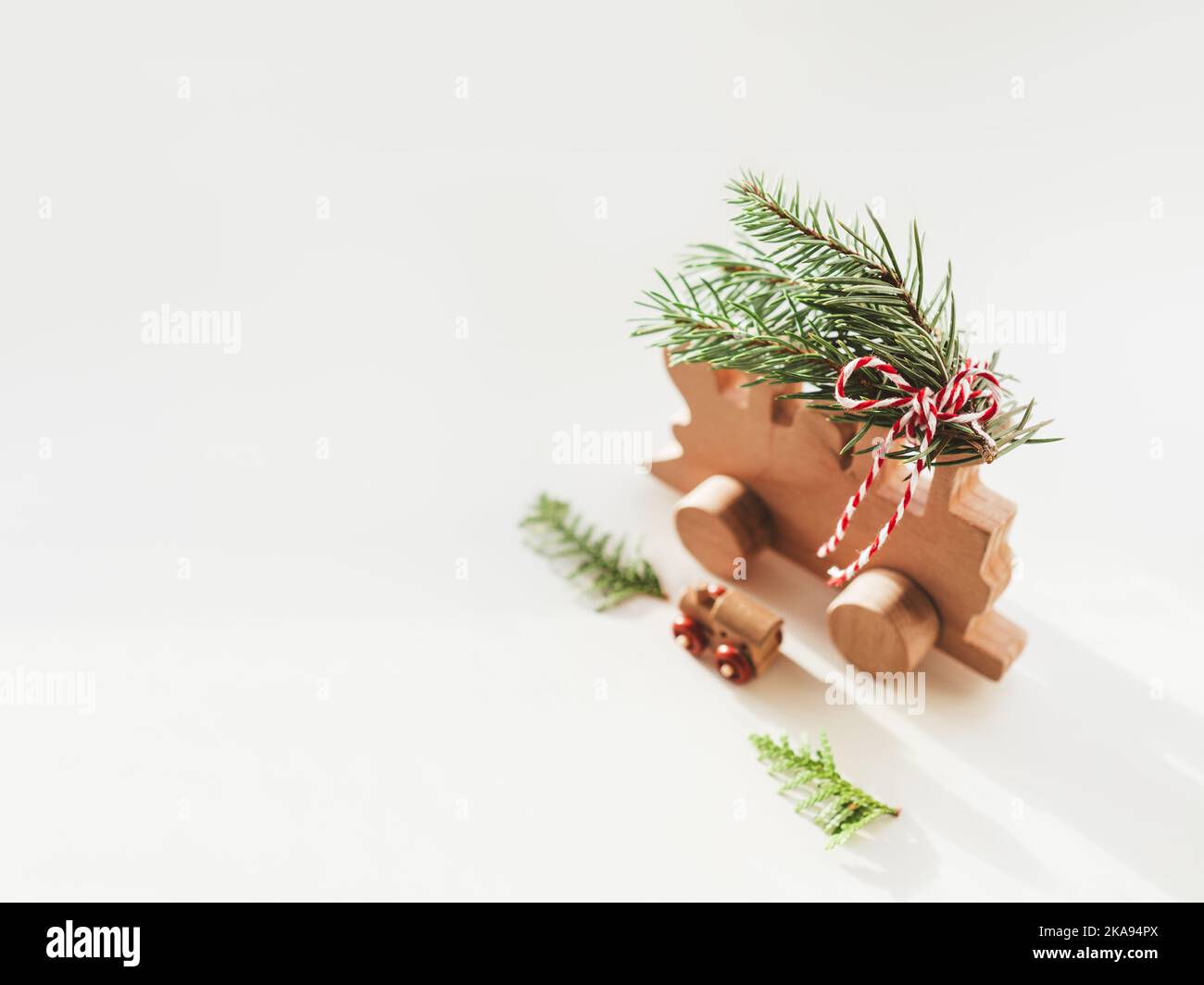 Two wooden trains with tied fir tree coniferous twigs. Dad and baby. Cute symbol of Christmas tree brought home for New Year celebration. Winter Stock Photo