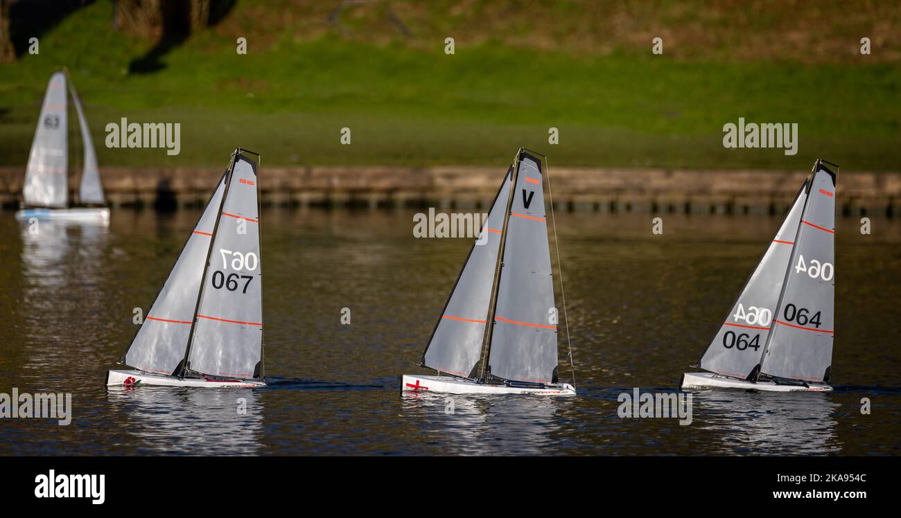 Three model yachts sailing in a row on Warminster Lake, Wiltshire, UK on 20 January 2022 Stock Photo