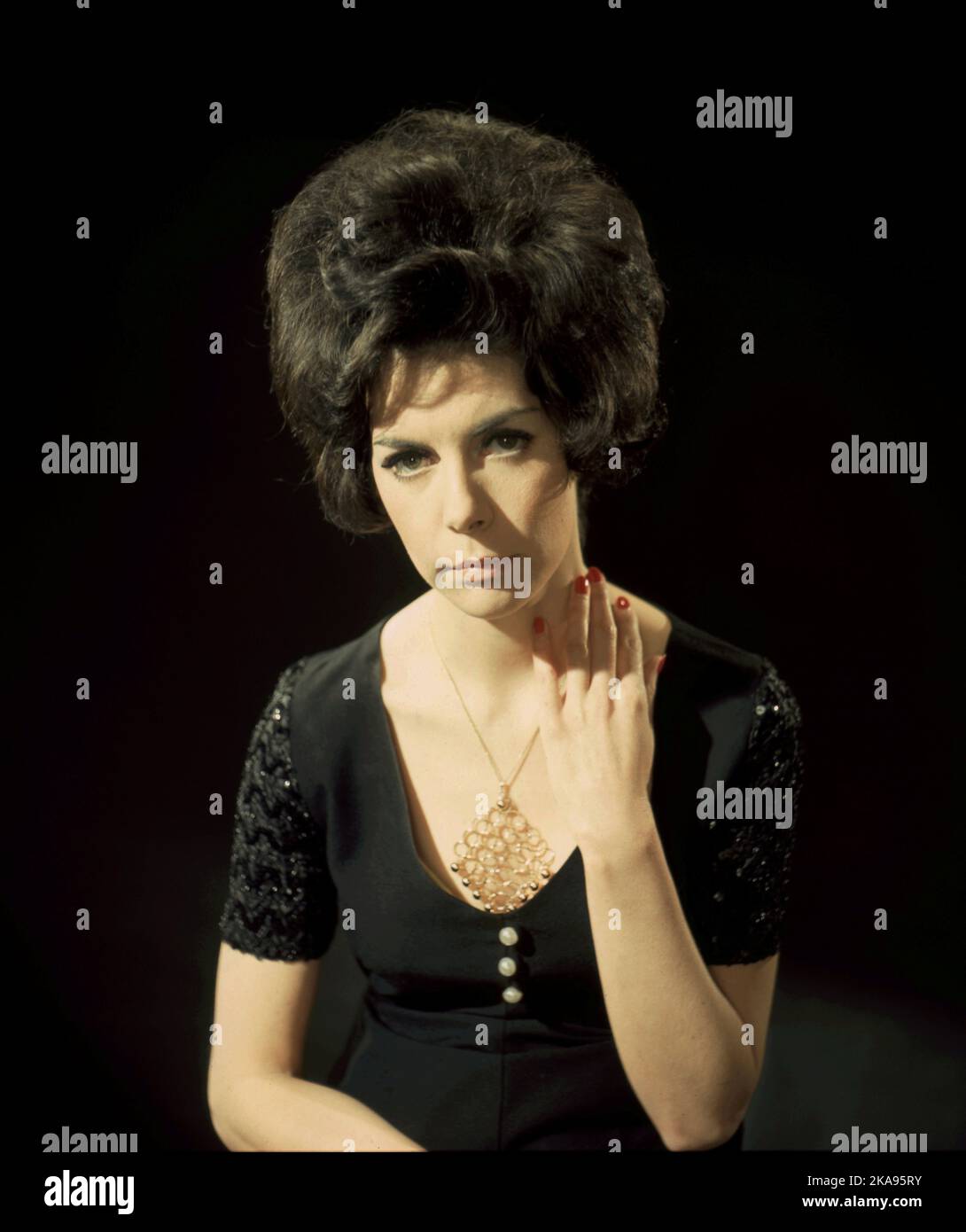 A woman in short-sleeved black evening dress with a large pendant necklance and bouffant hair, c1969 by Gilbert Adams (1906-1996), prominent third generation photographer, son of Marcus and grandson of Walton, Gilbert Adams trained with and assisted his father.   From the Gilbert Adams Collection of photography Copyright Tony Henshaw / Henshaw Archive Stock Photo