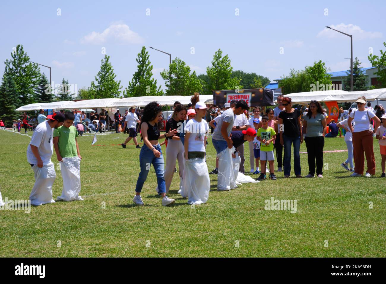 People having fun at gunnysack race on grass in a sunny day. Laughing ...