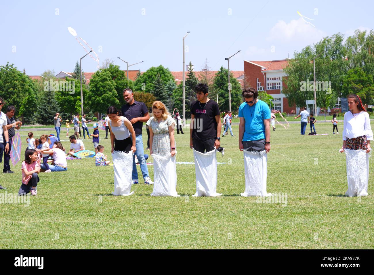 People having fun at gunnysack race on grass in a sunny day. Laughing ...