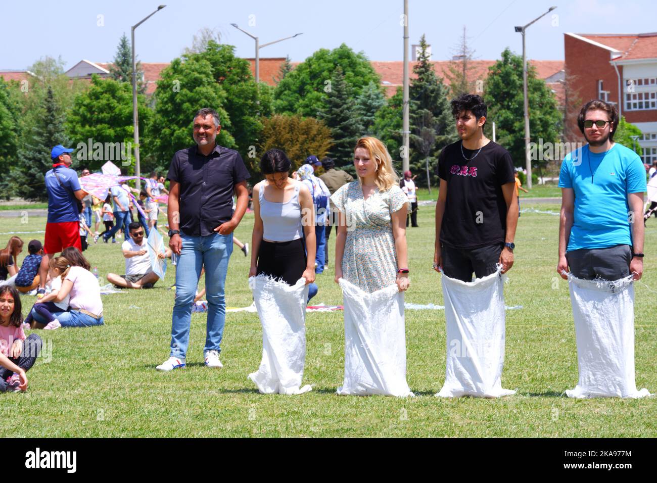 People having fun at gunnysack race on grass in a sunny day. Laughing ...