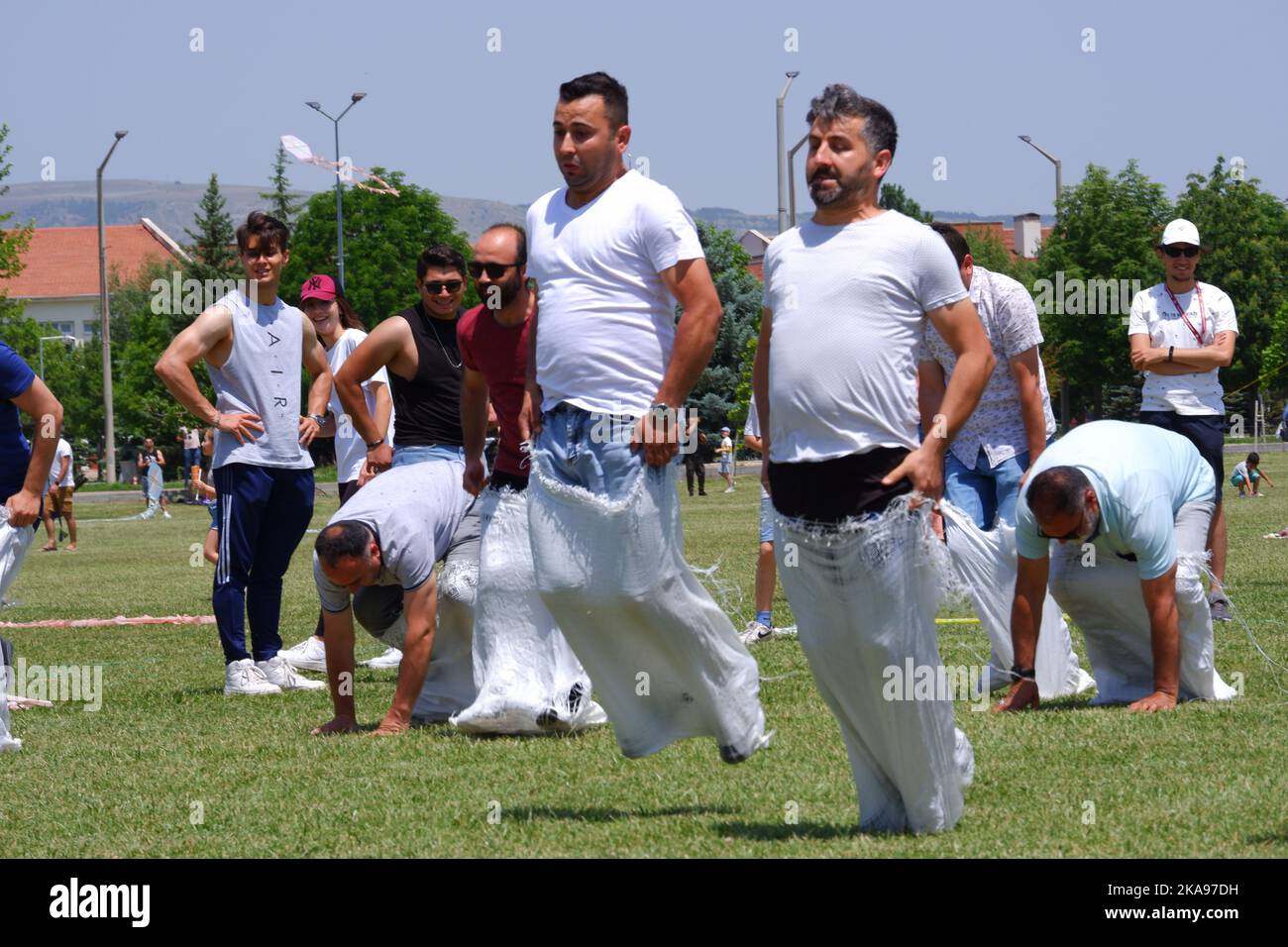 People having fun at gunnysack race on grass in a sunny day. Laughing ...