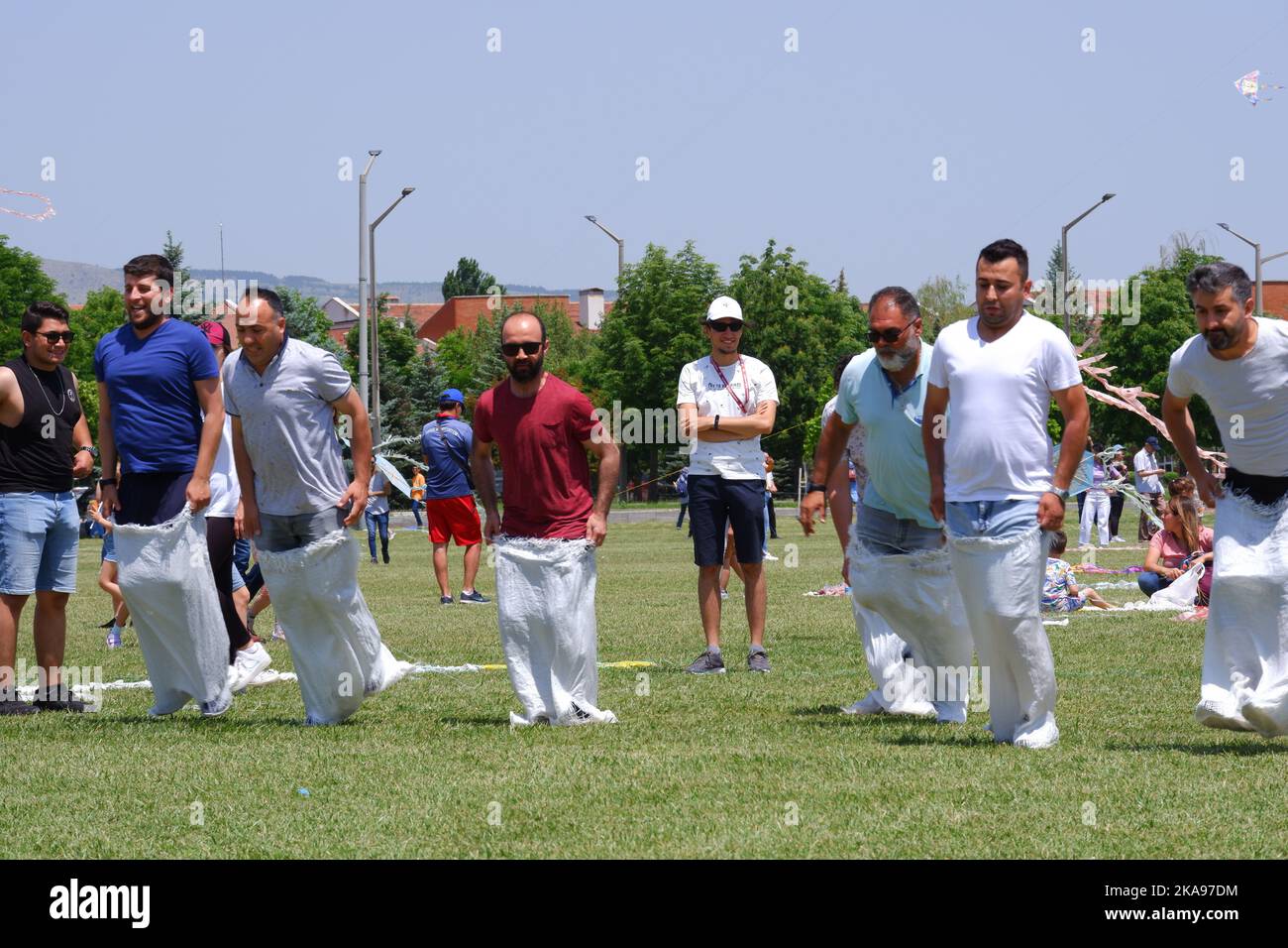 People having fun at gunnysack race on grass in a sunny day. Laughing ...