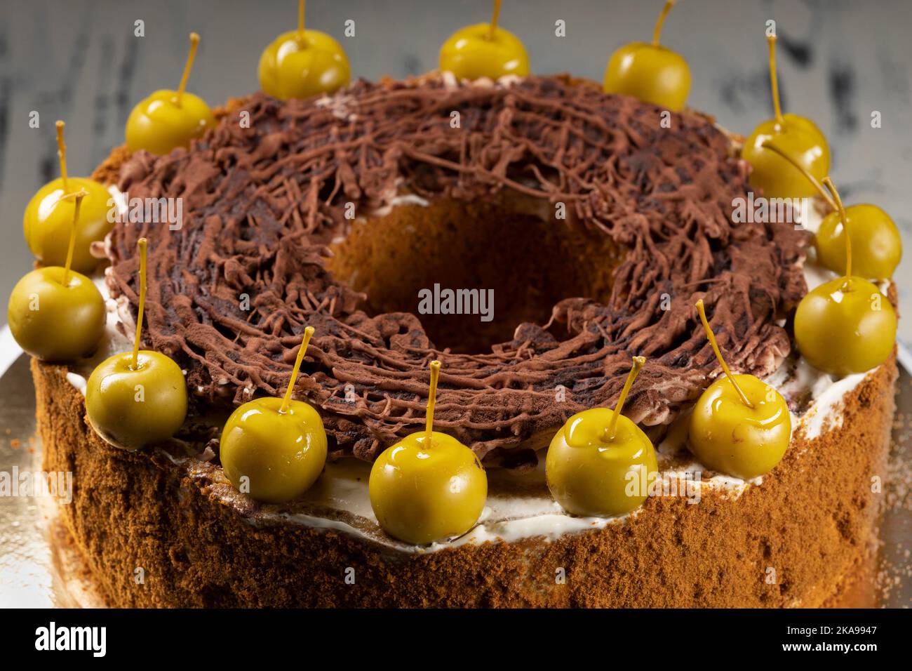 Homemade chocolate cake sweet pastry dessert with brown icing, green decorative cherries. Dark food photo, rustic style. Stock Photo