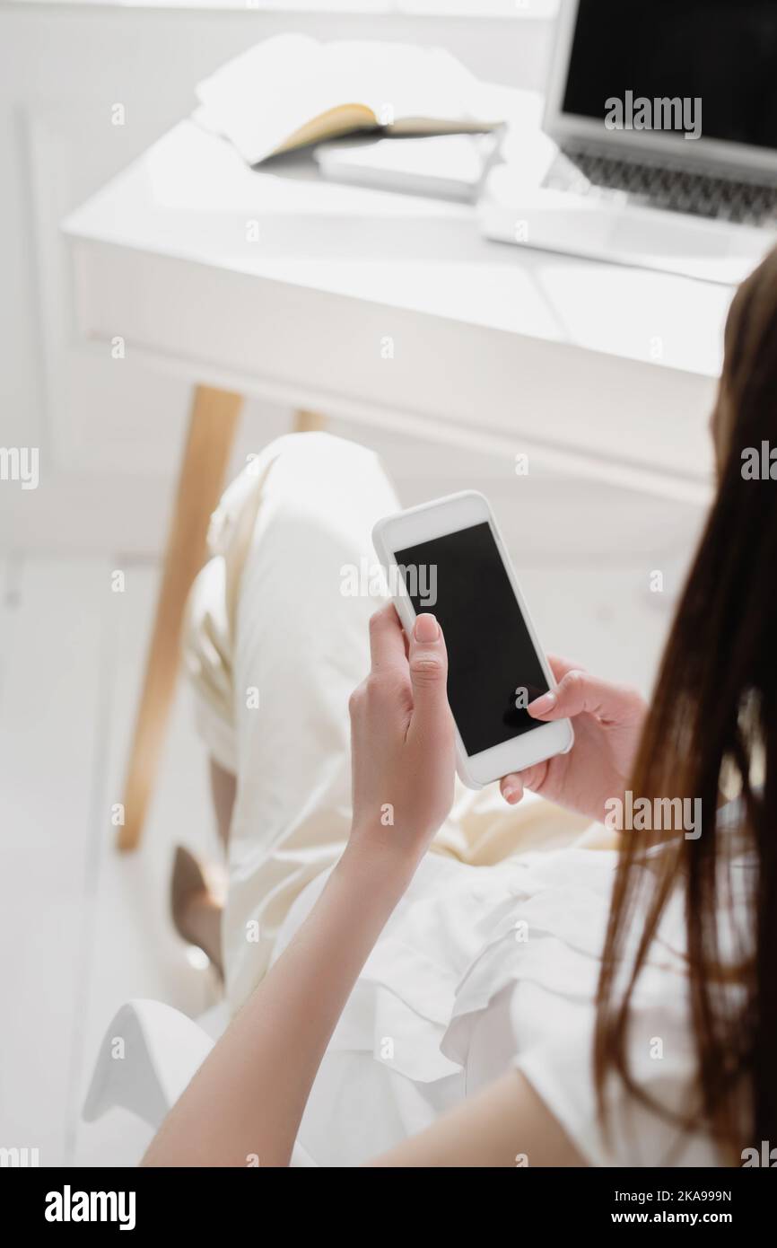 Back view of young business woman holding smartphone and looking at screen. Stock Photo
