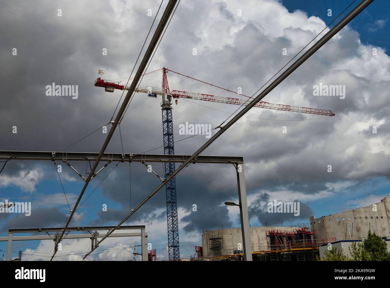A low angle shot of a crane under fluffy clouds on a construction side ...