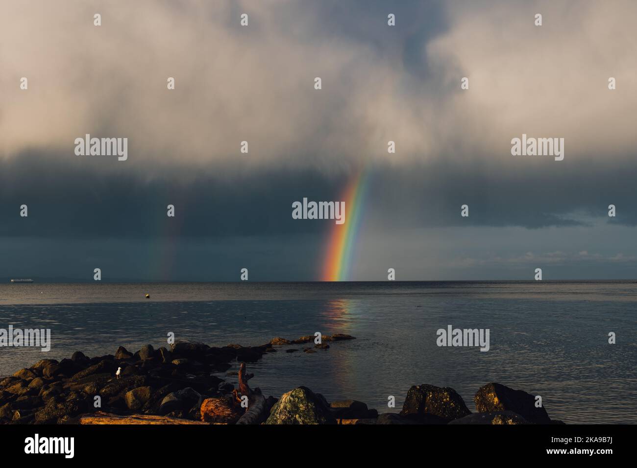 gray clouds with rainbow over the sea ocean Stock Photo