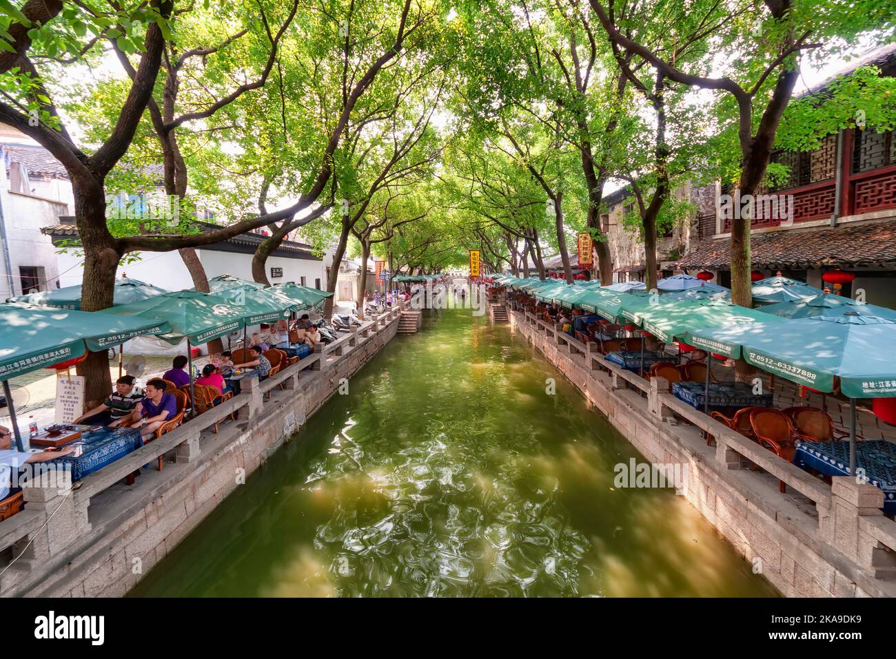 Tongli, China - August 13, 2011:  One of the many canals in Tongli with people sitting at restaurant tables. Tongli It is known for a system of canals Stock Photo