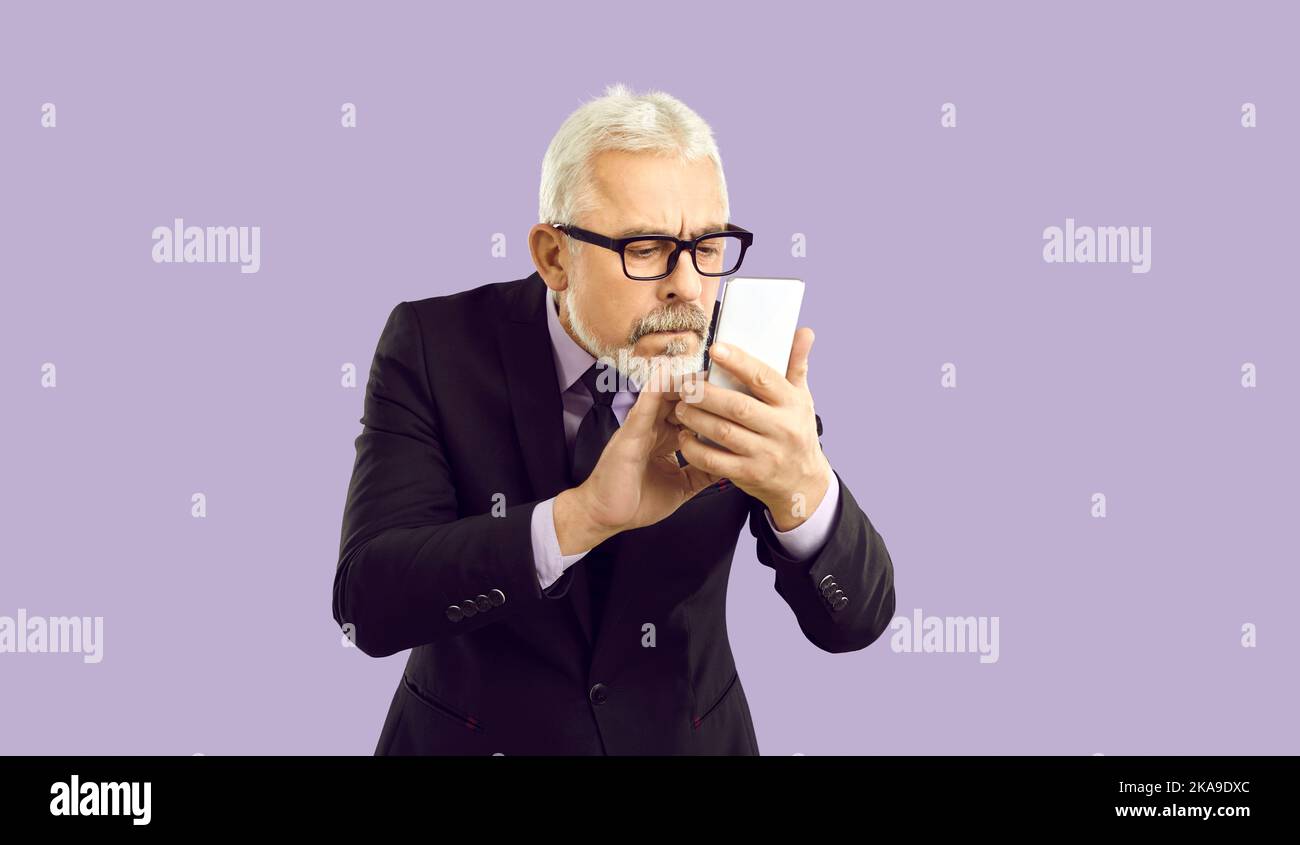 Aged businessman in glasses using cellphone Stock Photo