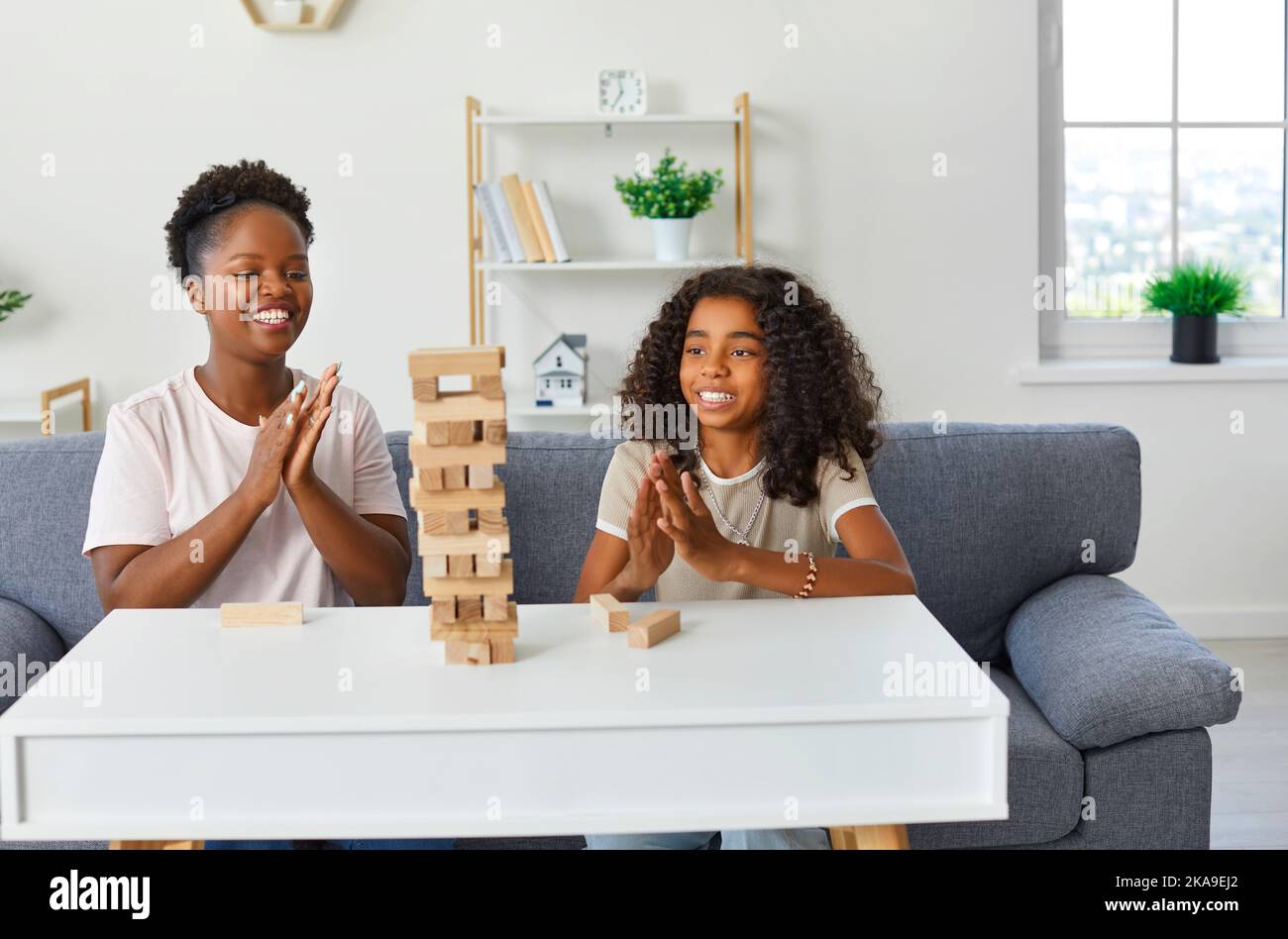 Happy mother and child sitting on couch at home, playing board game and having fun Stock Photo