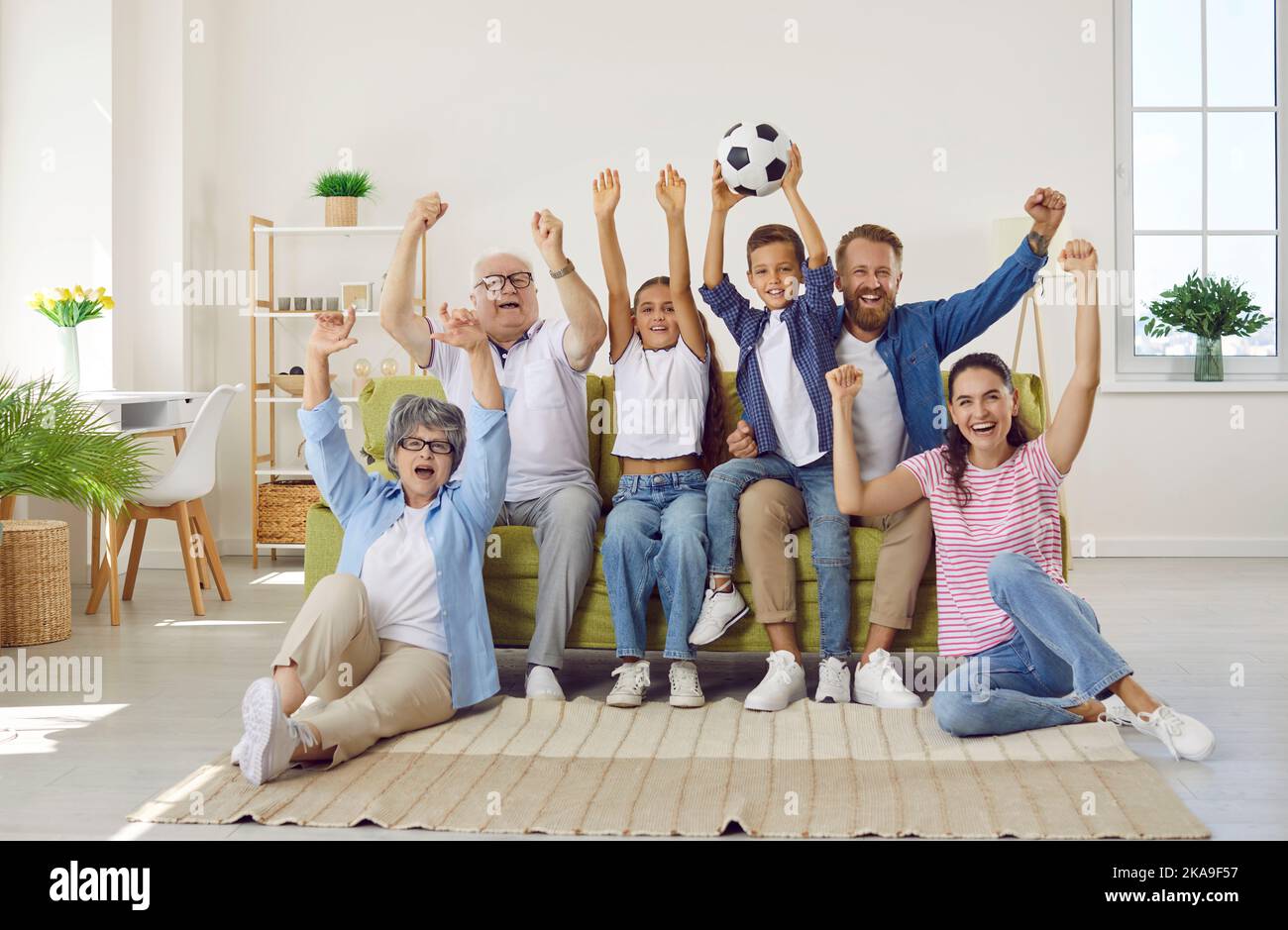 Excited happy big family showing win gesture while watching football championship on TV. Stock Photo