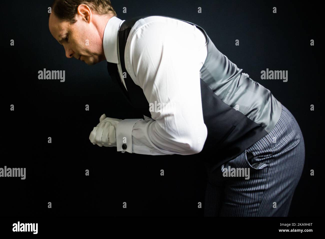 Portrait of Butler or Waiter in White Gloves and Vest Bowing in Respect