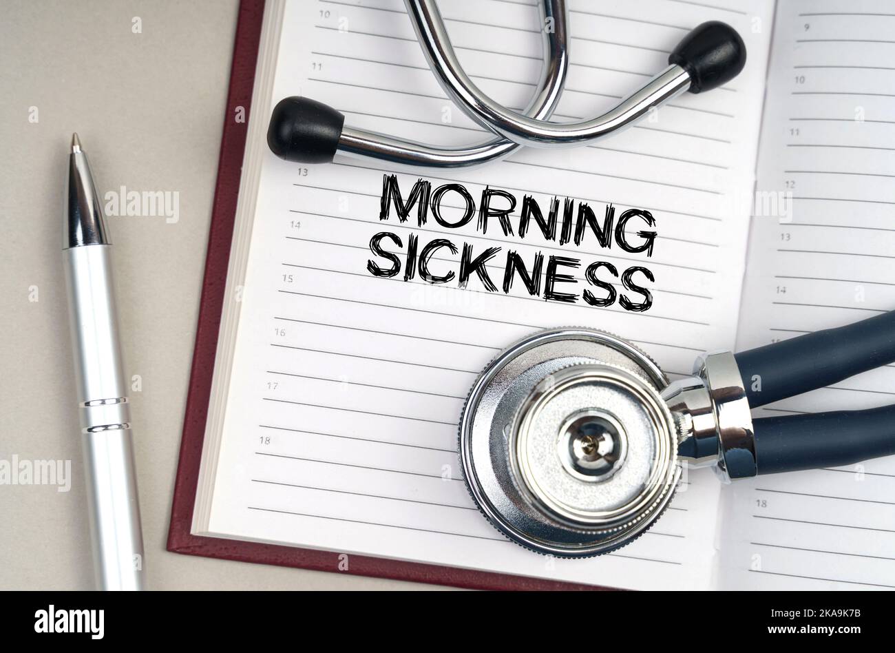 Medicine concept. On the table is a stethoscope, a pen and a notebook in which it is written - Morning Sickness Stock Photo