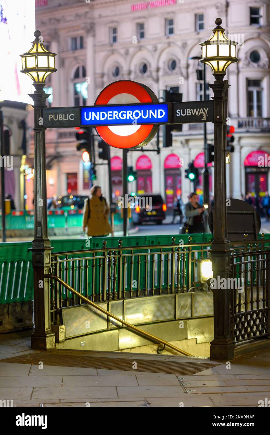 LONDON - November 3, 2020: London Underground Public Subway entrance to Piccadilly Tube Station illuminated at night with traffic out of focus in the Stock Photo
