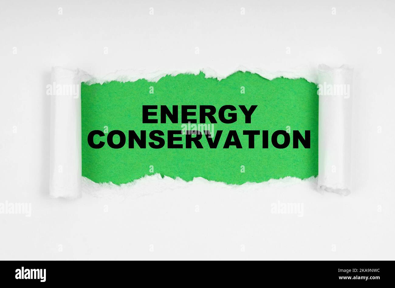 Environmental concept. In the middle of the white sheet, the paper is torn, inside on a green background the inscription - Energy Conservation Stock Photo