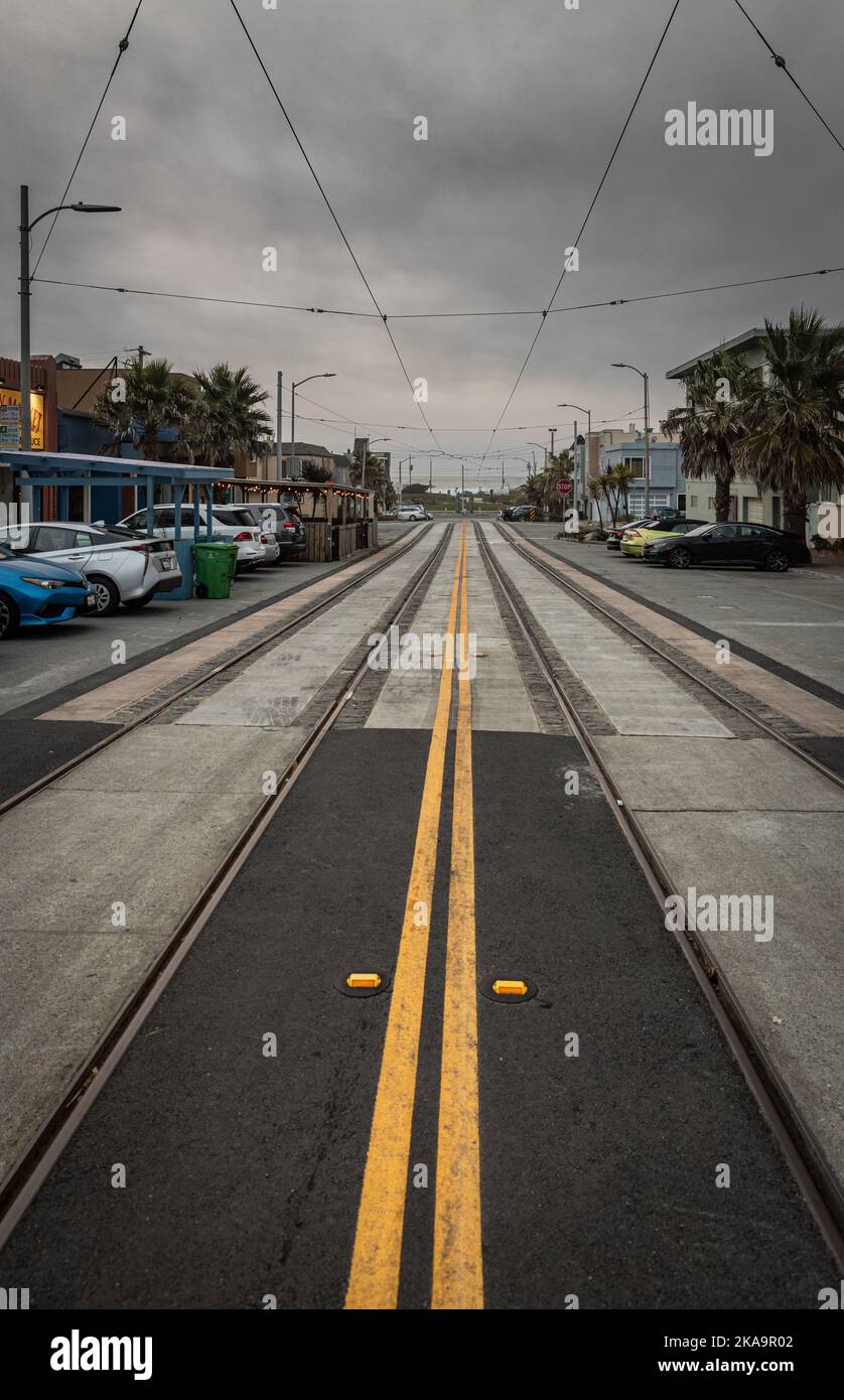 A vertical shot of cars parked at an asphalt road with trolley tracks ...