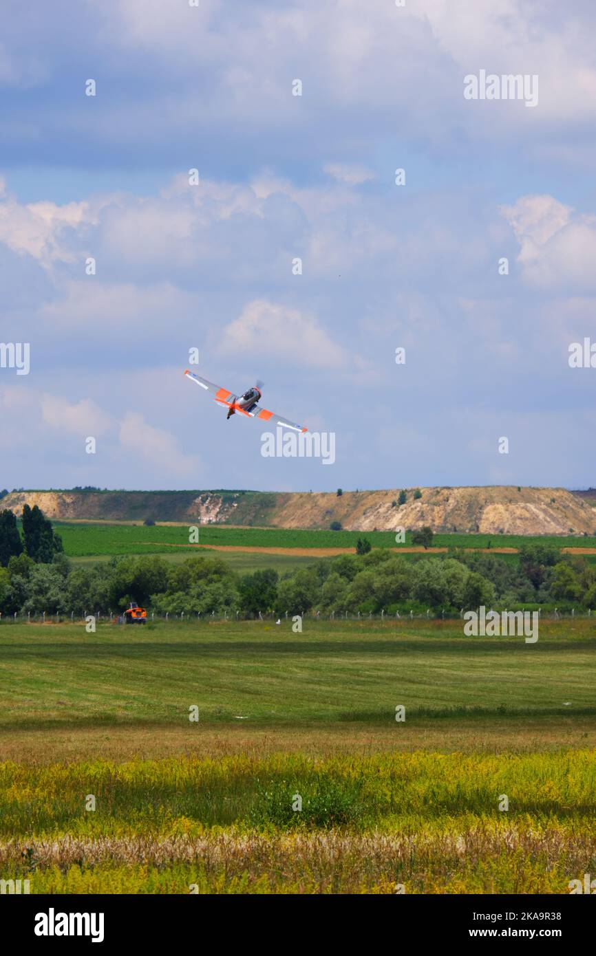Small airplane taking off from grass and climbing at a cloudy day Stock Photo