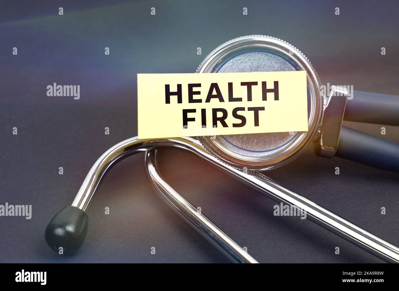 Medicine concept. On a black background, a stethoscope, on which a sticker with the inscription - HEALTH FIRST Stock Photo