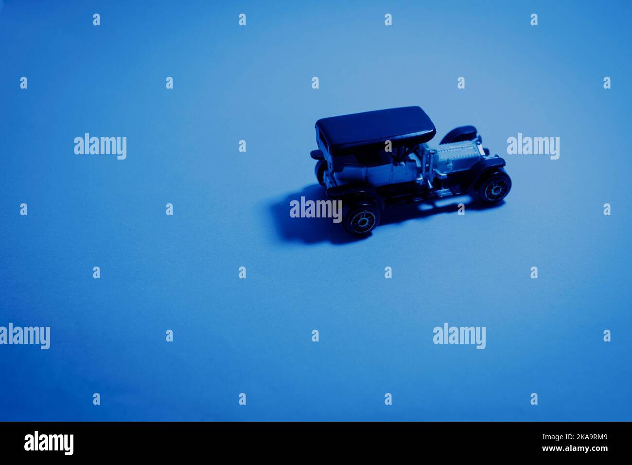 A vintage jeep toy car with a shadow on a table under blue light Stock Photo