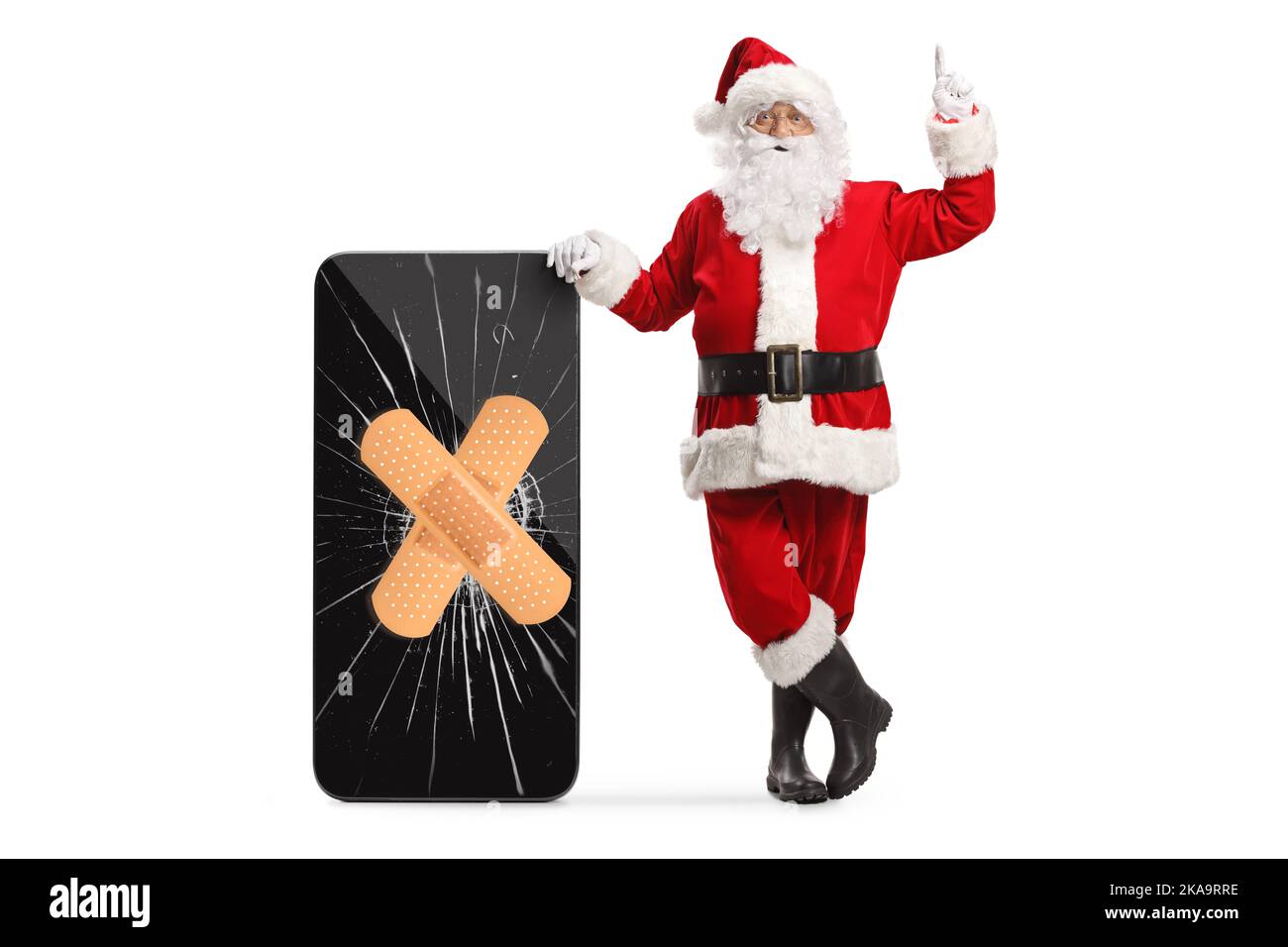 Santa claus pointing up and leaning on a smartphone with bandage on a cracked screen isolated on white background Stock Photo