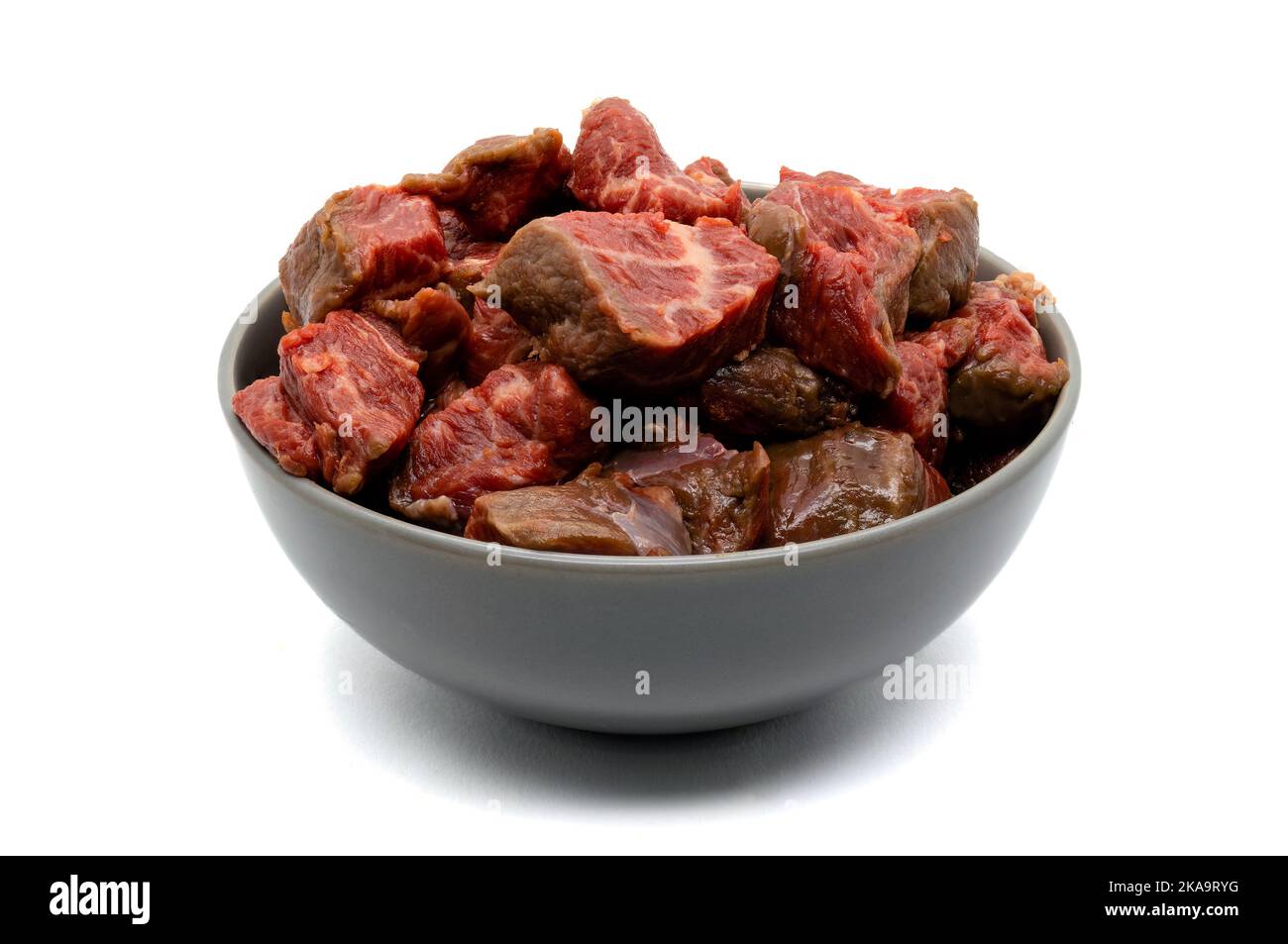 Bowl of raw diced red meat isolated on white background Stock Photo