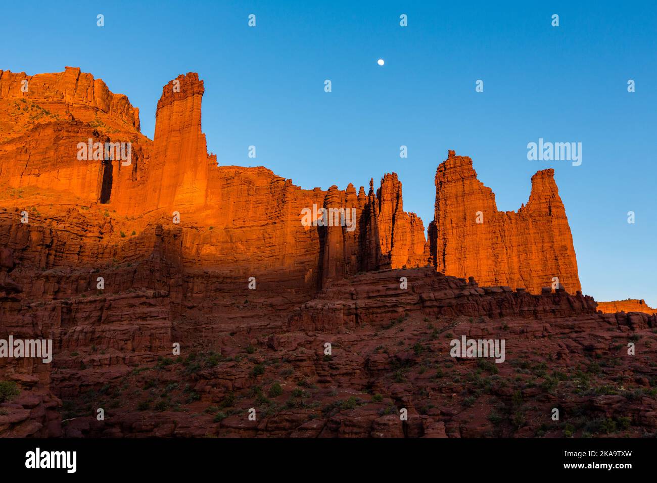 Rising moon over the Fisher Towers at sunset.  L-R: The Kingfisher Tower, the Cottontail & the Titan are at right.  Moab, Utah. Stock Photo