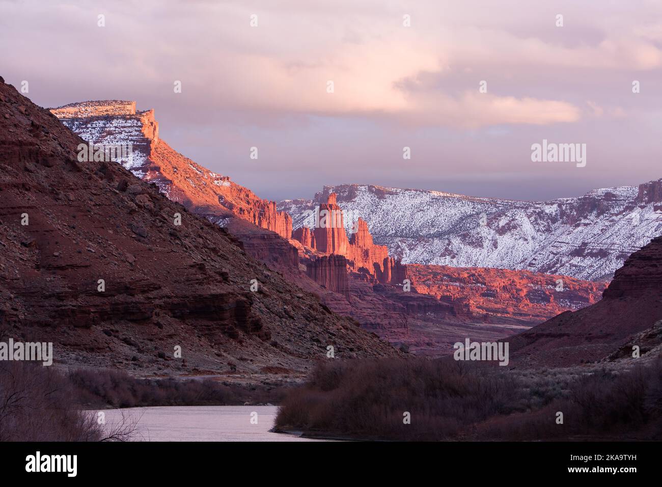 Fisher Towers over the Colorado River at sunset in winter with the La Sal Mountains behind.  Near Moab, Utah. Stock Photo