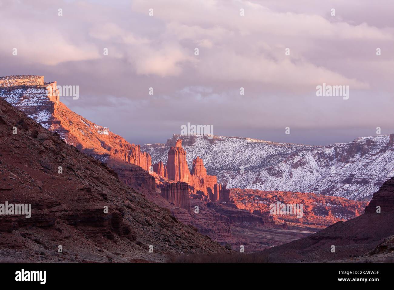 Fisher Towers over the Colorado River at sunset in winter with the La Sal Mountains behind.  Near Moab, Utah. Stock Photo